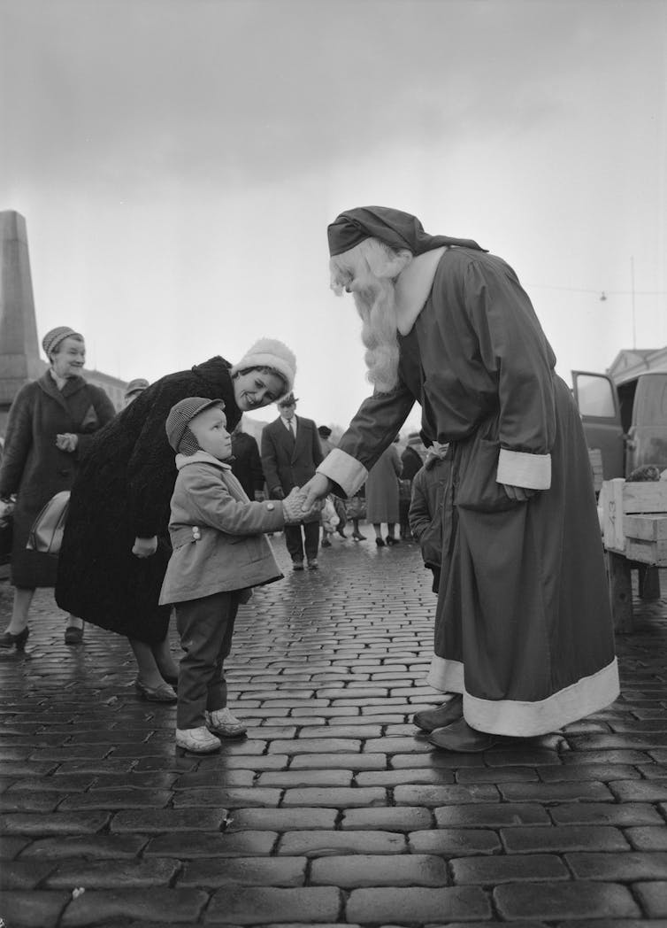 Santa menjabat tangan seorang anak laki-laki.