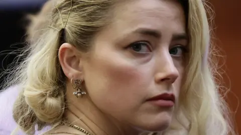 Reuters Tampilan jarak dekat dari Amber Heard yang menghadap ke satu sisi di pengadilan pada tahun 2022 