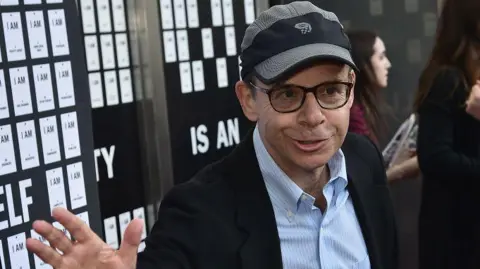 Getty Images Rick Moranis - Penampakan langka di malam pembukaan teater di New York pada tahun 2017. Dia mengenakan setelan hitam, kemeja biru muda, kacamata dan topi baseball khasnya.