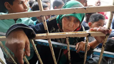 Reuters Seorang wanita Palestina berdiri di toko roti yang telah berhenti beroperasi karena kurangnya tepung dan bahan bakar, di Kota Gaza (1 April 2026)