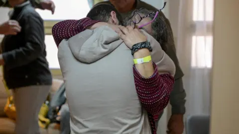 Reuters Yarden Bibas dipersatukan kembali dengan orang -orang yang dicintainya di Sheba Medical Center di Ramat Gan, Israel. Dia mengenakan hoodie abu -abu dan punggungnya ke kamera saat dia memeluk seorang anggota keluarga. 