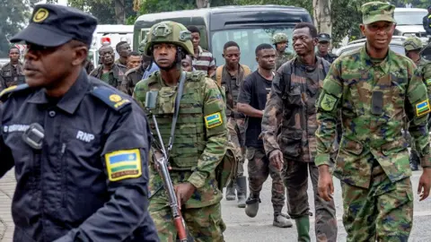 Reuters Seorang polisi Rwanda dan tentara tentara Rwanda mengawal sekelompok tentara Kongo ke Gisenyi setelah mereka menyerah