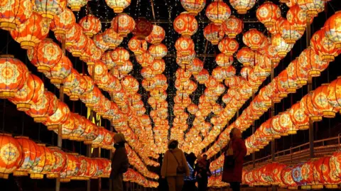 Getty Images Pengunjung menikmati lentera merah menyala untuk merayakan festival musim semi di Cina
