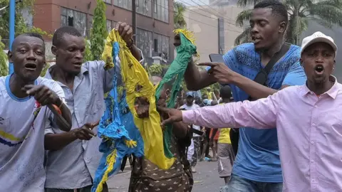 EPA lima pria di Kinshasa merobek bendera Rwanda saat mereka berteriak sebagai protes tentang serangan Goma M23 di DR Kongo - 28 Januari 2025