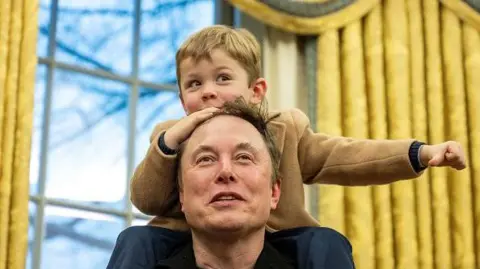 Getty Images Putra Elon Musk, X, duduk di pundaknya di kantor oval